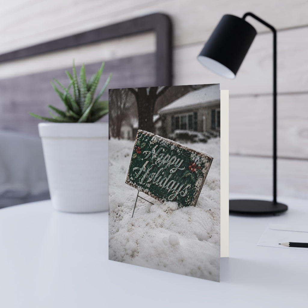 Forecast / The forecast called for snow. It didn't mention quiet. The holiday greeting is still there, half covered, leaning into another winter day, waiting for the next passerby. / Holiday Greeting Card